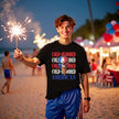 Male model wearing black Cold-Blooded American t-shirt on the beach, skull ice cream cone graphic with red white blue drip and distressed lettering, bold summer vibe