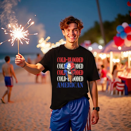 Male model wearing black Cold-Blooded American t-shirt on the beach, skull ice cream cone graphic with red white blue drip and distressed lettering, bold summer vibe