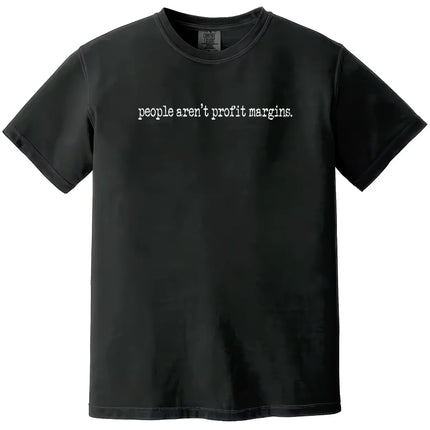 Black “People Aren’t Profit Margins” t-shirt flat lay showcasing minimalist font and bold people-over-profits message
