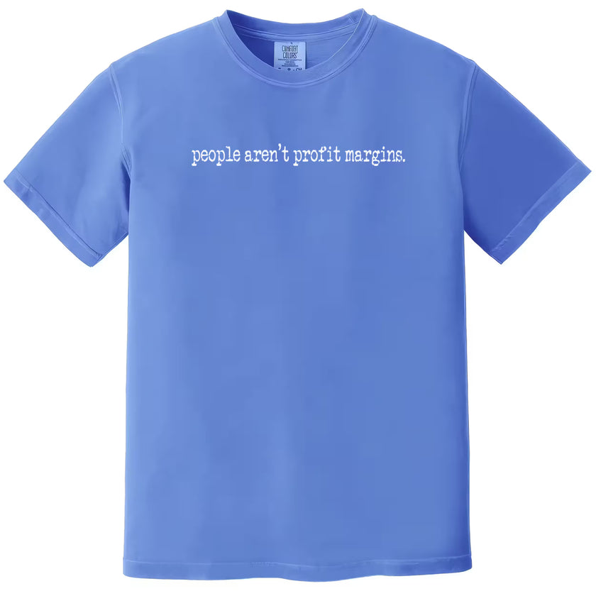 Blue “People Aren’t Profit Margins” t-shirt flat lay with simple lettering and strong ethical message