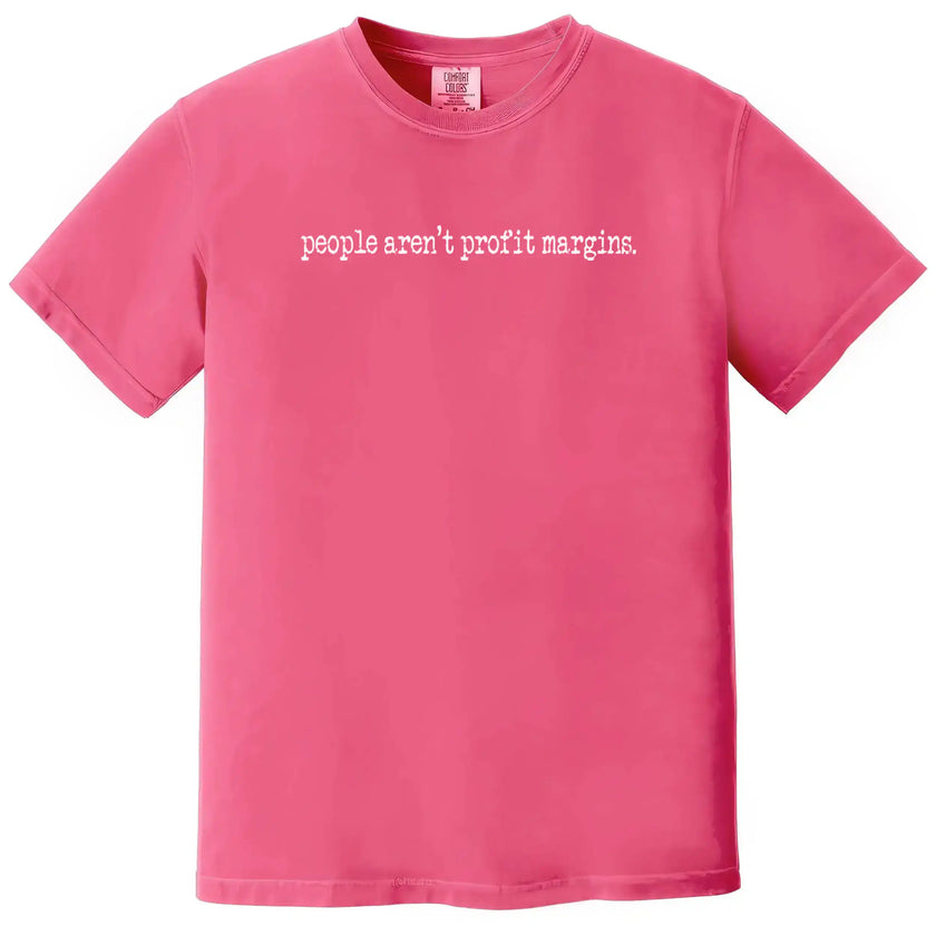 Pink “People Aren’t Profit Margins” t-shirt flat lay combining soft color with bold social values message