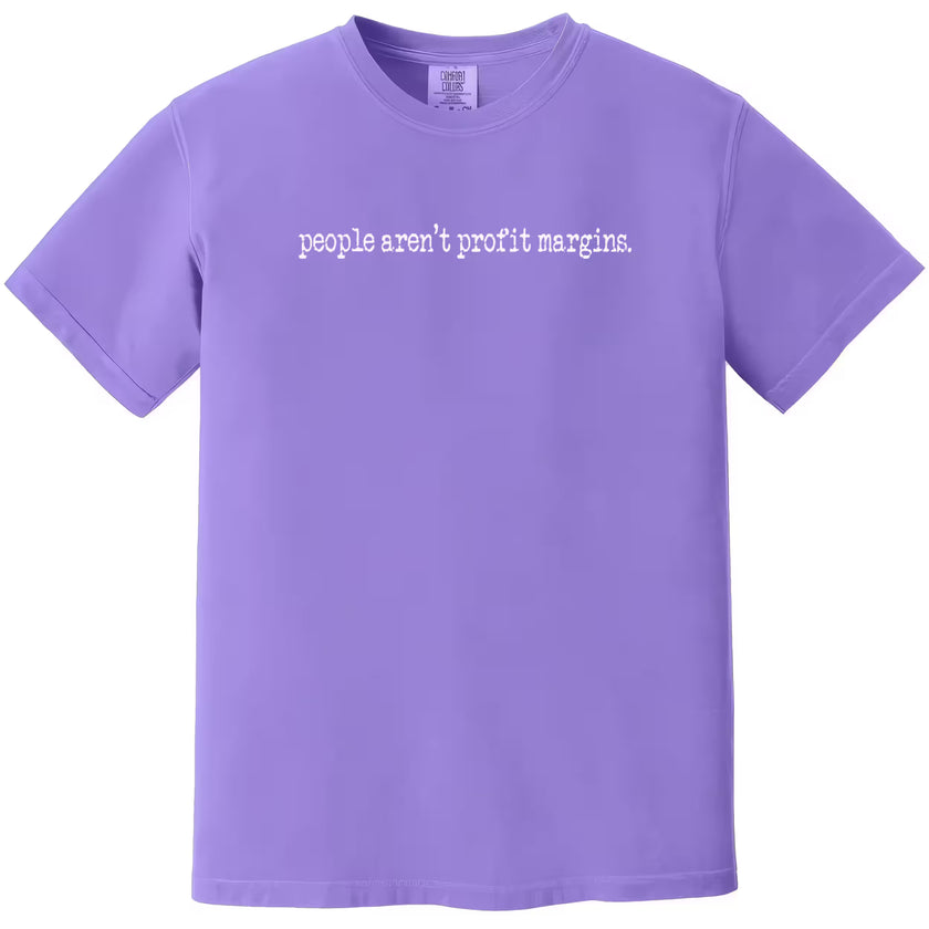 Purple “People Aren’t Profit Margins” t-shirt flat lay highlighting clean minimalist text and advocacy-focused design