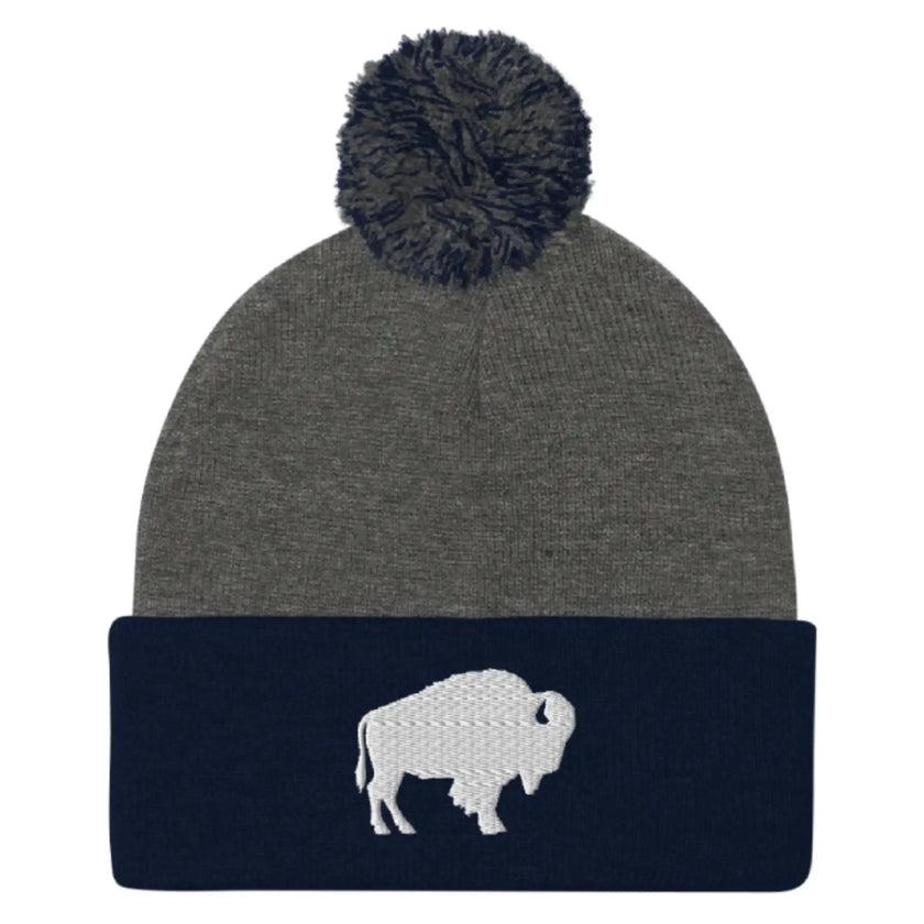 Navy and grey pom pom beanie featuring embroidered Buffalo silhouette logo, clean Buffalo city inspired winter hat design.