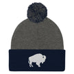 Navy and grey pom pom beanie featuring embroidered Buffalo silhouette logo, clean Buffalo city inspired winter hat design.