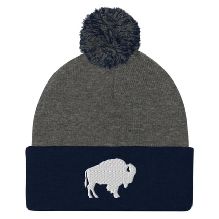 Navy and grey pom pom beanie featuring embroidered Buffalo silhouette logo, clean Buffalo city inspired winter hat design.
