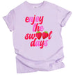 Cute summer graphic tee in purple, retro ‘Enjoy the Sweet Days’ lettering with strawberry detail, playful seasonal shirt.
