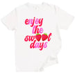 Cute strawberry summer tee in white, ‘Enjoy the Sweet Days’ retro pink and red lettering with fruit detail design.