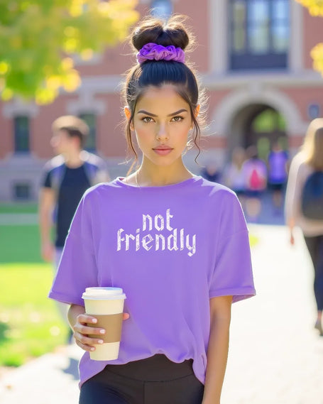 College female model holding latte on campus wearing purple ‘Not Friendly’ pun t-shirt, featured as cover image for funny pun graphic tee collection showcasing humorous statement apparel.