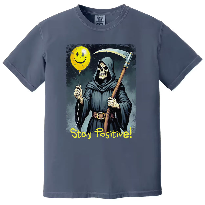 Blue “Stay Positive” grim reaper t-shirt flat lay highlighting ironic dark humor illustration and bold sarcastic message