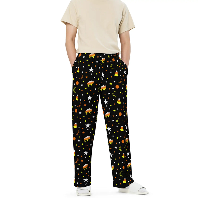 Man wearing black Halloween lounge pants featuring festive Buffalo print with orange yellow white candy corn colors, cozy seasonal style, and spooky themed pattern.