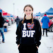 Female model wearing black Buffalo ‘I ♥ BUF’ sweatshirt in the snow, bold white lettering with striped heart and bow, cozy winter fan look.