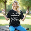 Female model wearing black “If I’m too much then go find less” t-shirt outdoors, layered typography design, confident sassy women’s casual outfit.