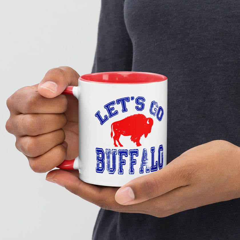 Close-up of hand gripping white ceramic Buffalo football coffee mug with sharp view of distressed blue lettering and red buffalo design