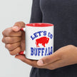 Close-up of hand gripping white ceramic Buffalo football coffee mug with sharp view of distressed blue lettering and red buffalo design