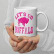 Close-up of white ceramic coffee cup with hot pink distressed ‘Lets Go Buffalo’ text and buffalo silhouette graphic in center, Buffalo football themed drinkware.