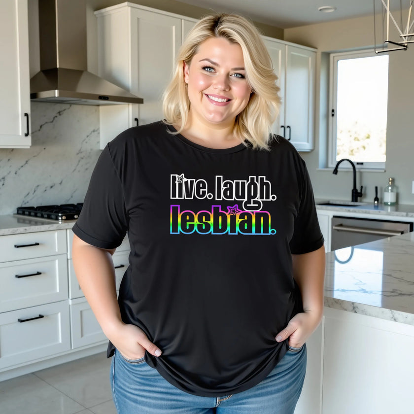 Female model wearing black ‘Live Laugh Lesbian’ t-shirt outdoors, retro rainbow accent lettering, cute casual Pride aesthetic outfit.