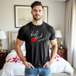 Male model wearing black Best Dick Ever tee with red lips graphic in hotel room, posing confidently and sexy