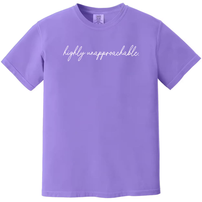 Purple “Highly Unapproachable” t-shirt flat lay highlighting clean script lettering and confident humor