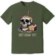 Green “Not Dead Yet” t-shirt flat lay with skull, candle, rainbow sprinkles, and cake, sarcastic birthday design for milestone celebrations