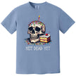 Light blue “Not Dead Yet” t-shirt flat lay showcasing skull with lit candle, rainbow sprinkles, and birthday cake slice, funny and dark humor tee