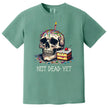 Green “Not Dead Yet” t-shirt flat lay with skull and lit birthday candle, rainbow sprinkles, and cake slice, dark humor birthday tee