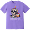 Purple “Not Dead Yet” t-shirt flat lay featuring skull with lit candle, rainbow sprinkles, and cake slice, cheeky birthday humor design
