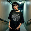 Female model wearing black retro pixel sarcastic graphic tee outdoors, bold edgy humor statement design, casual funny outfit.