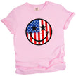 Cute patriotic smiling face shirt in pink, American flag paint splatter design with star eyes, playful July 4th tee.