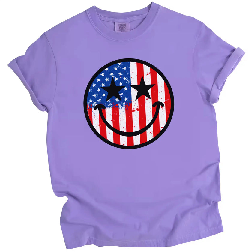 Funny patriotic t-shirt in purple, smiling face filled with American flag paint splatter and star eyes, casual July 4th shirt.