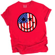 Patriotic smiling face t-shirt in red, American flag paint splatter design with star-shaped eyes, fun July 4th graphic tee