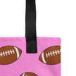 Close-up of pink tote fabric showing detailed repeating brown football pattern in alternating sizes, playful sports-inspired design.