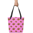 Hand holding a pink football print tote bag featuring repeating brown footballs in multiple sizes, versatile carryall for shopping, groceries, books, and travel.