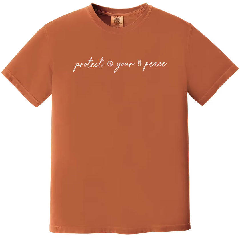 Orange “Protect Your Peace” t-shirt flat lay with fancy script font and small peace symbols, perfect for relaxed everyday wear