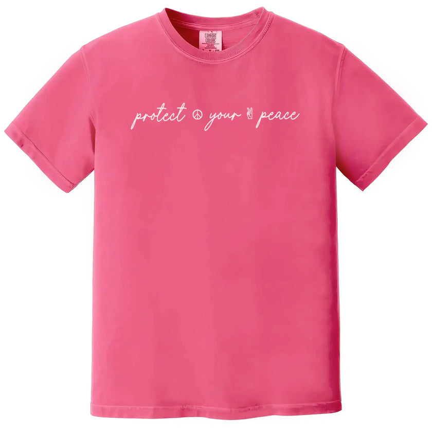Pink “Protect Your Peace” t-shirt flat lay combining elegant script lettering with minimalist peace icons for soft, calming style