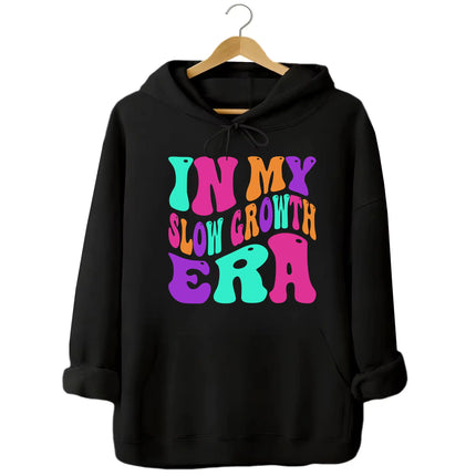 Black “In My Slow Growth Era” hoodie featuring colorful retro neon text, positive mindset design for relaxed, confidence-forward style