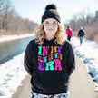 Female model wearing black “In My Slow Growth Era” hoodie in a casual lifestyle setting, cozy and confident look celebrating personal growth