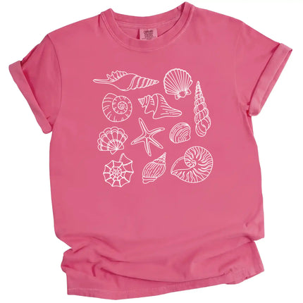 Seashell summer t-shirt in pink, featuring detailed ocean shell varieties arranged in a soft feminine coastal aesthetic layout.