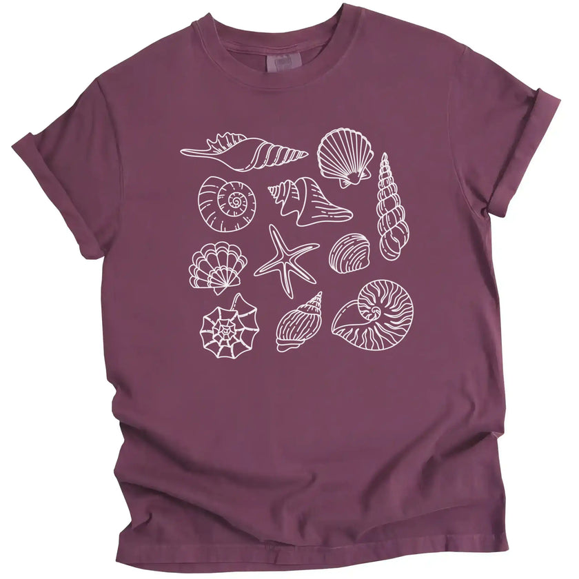 Seashell graphic tee in maroon, featuring multiple detailed seashell varieties arranged in a soft coastal summer aesthetic layout.