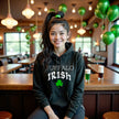 Female model wearing black Buffalo Irish hoodie sitting at a bar celebrating St. Patrick’s Day