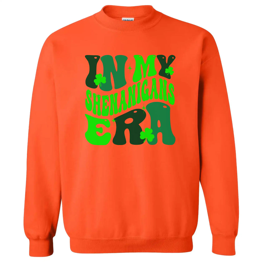 Orange “In My Shenanigans Era” St. Patrick’s Day sweatshirt flat lay showcasing whimsical font and shamrock accents for fun March style
