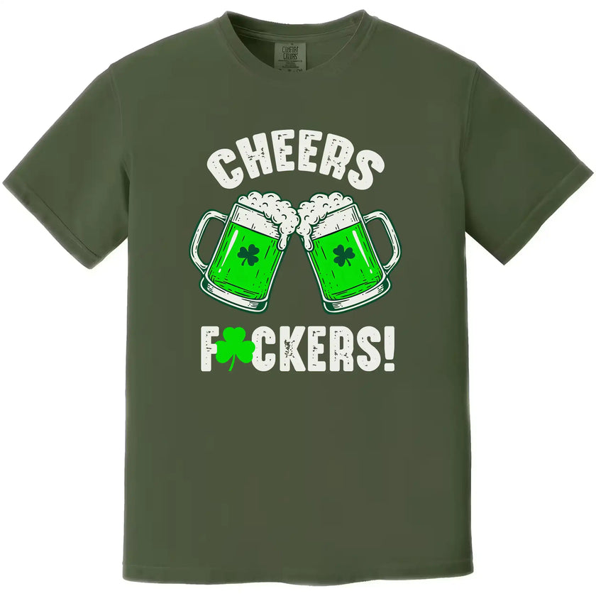 Green St. Patrick’s Day “Cheers Fuckers!” t-shirt flat lay with bold holiday-themed lettering and clinking green beer mugs