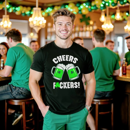 Male model wearing black “Cheers Fuckers!” St. Patrick’s Day t-shirt standing at a pub celebrating the holiday