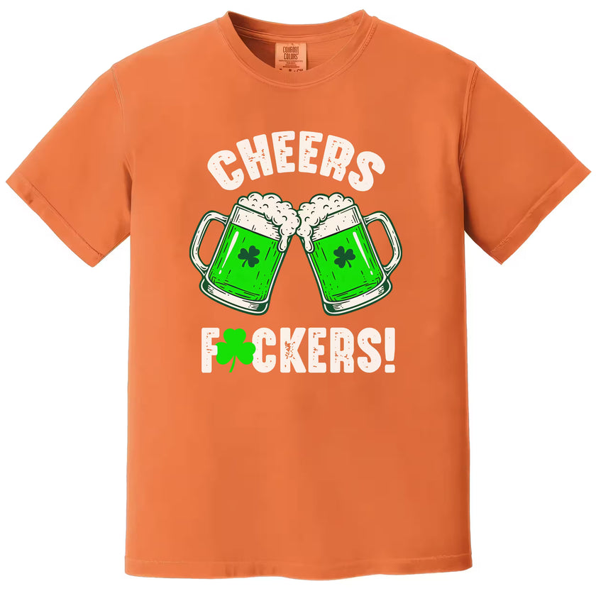 Orange “Cheers Fuckers!” St. Patrick’s Day t-shirt flat lay highlighting playful green beer mugs and festive shamrock accent