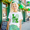 Female model wearing white St. Patrick’s Day LOVE t-shirt standing outside in front of an Irish pub 