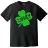 Black St. Patrick’s Day Lucky t-shirt flat lay featuring a large four-leaf clover and distressed “Lucky” lettering