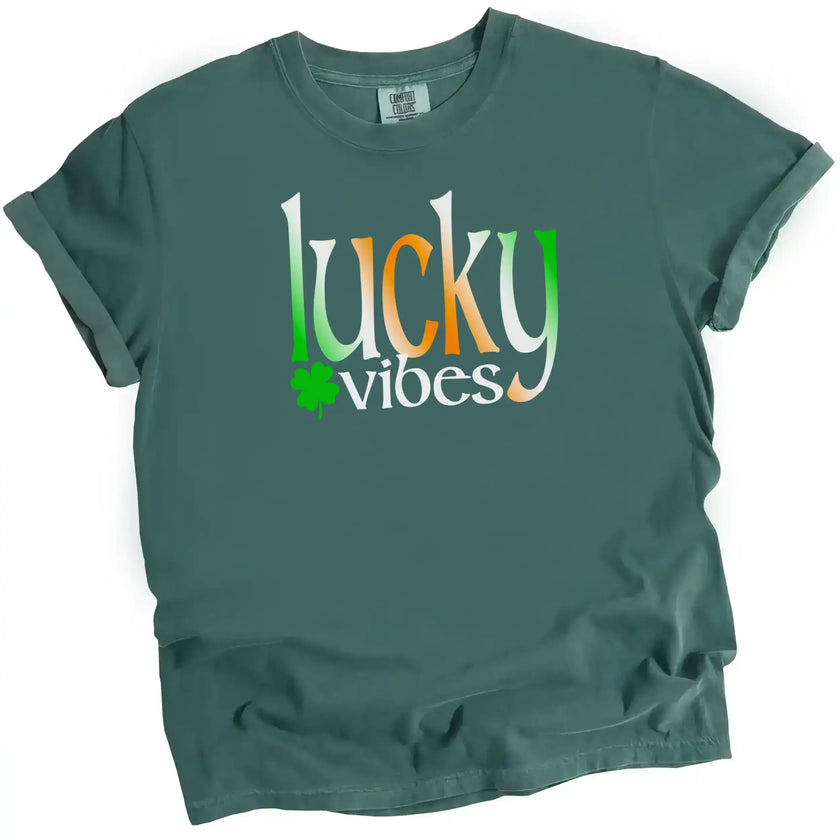 Blue-green St. Patrick’s Day Lucky Vibes t-shirt flat lay featuring bold Irish-colored gradient letters with clover accent