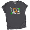 Gray Lucky Vibes St. Patrick’s Day t-shirt flat lay featuring vibrant Irish-colored lettering and small clover design for festive style