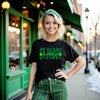 Female model wearing black St. Paddy Baddie t-shirt standing outside in front of an Irish pub celebrating St. Patrick’s Day