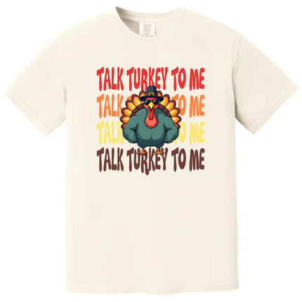 Cream colored Thanksgiving t-shirt featuring ‘Talk Turkey to Me’ text with playful turkey wearing sunglasses and big muscles graphic for festive fall apparel.