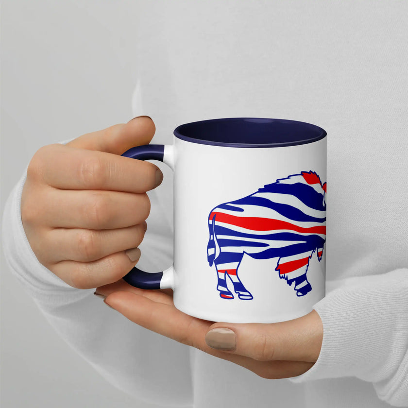 Hand holding white Buffalo football coffee mug featuring ‘The Mafia Runs Buffalo’ design with red white and blue buffalo silhouette, sports fan drinkware for game day use.